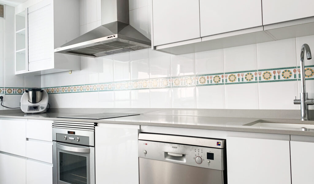 Cocina blanca con isla reformada por Fustecma