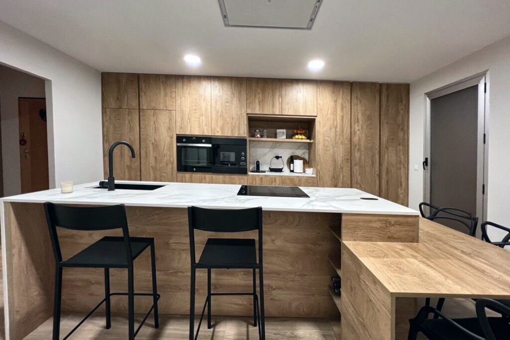 Isla con placa de inducción, fregadero y barra con taburetes