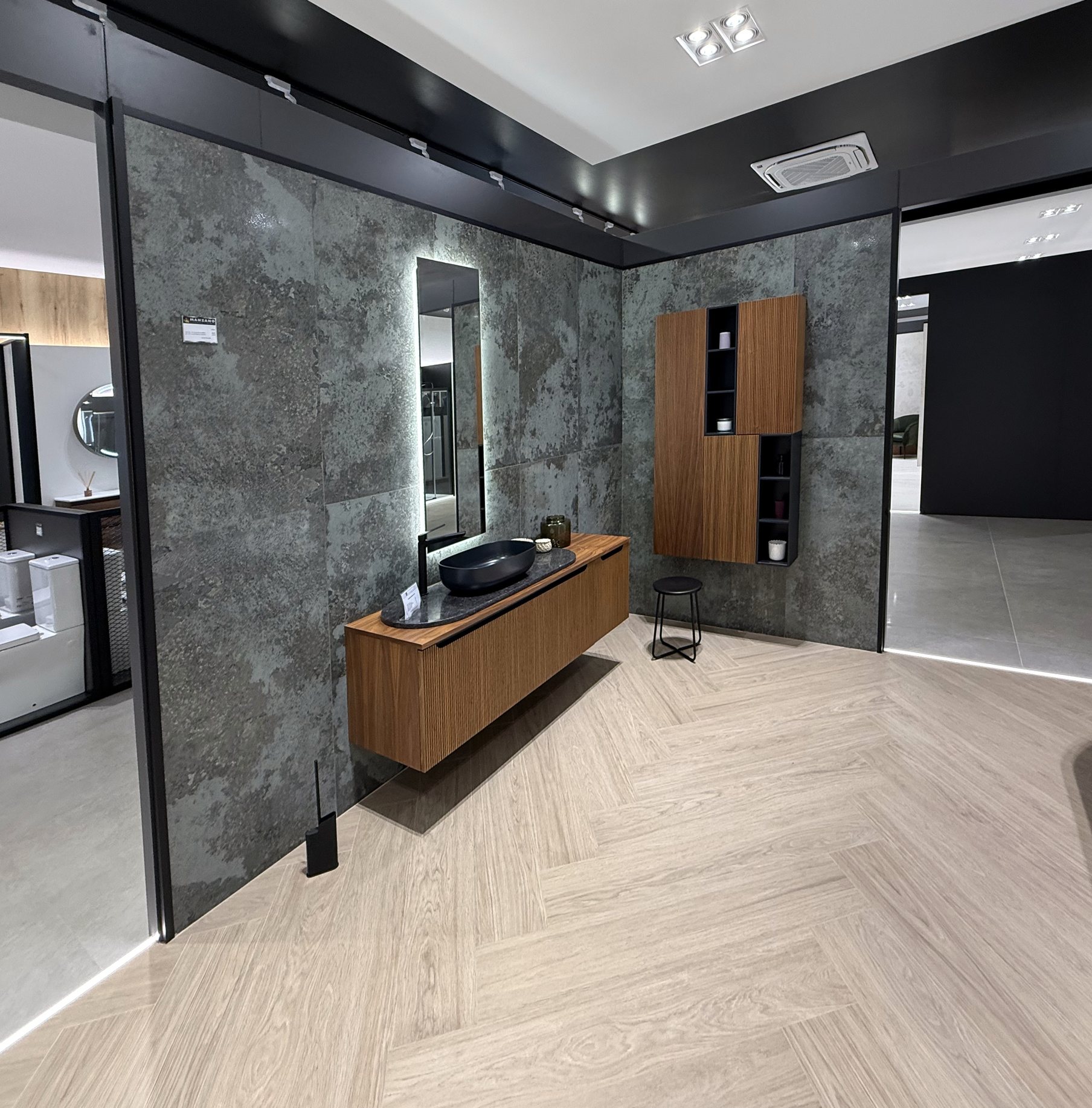 Ambiente de baño con revestimiento de piedra oscura y mueble de madera