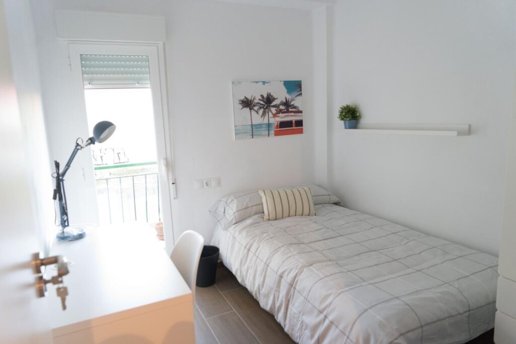 Dormitorio individual con escritorio junto a la ventana