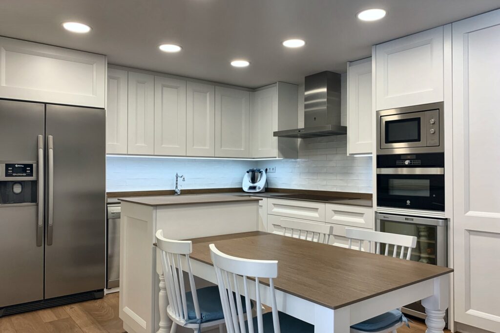 Cocina blanca con frentes enmarcados y mesa central