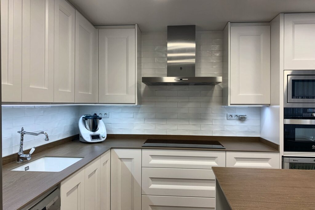 Cocina en L con fregadero bajo encimera y campana