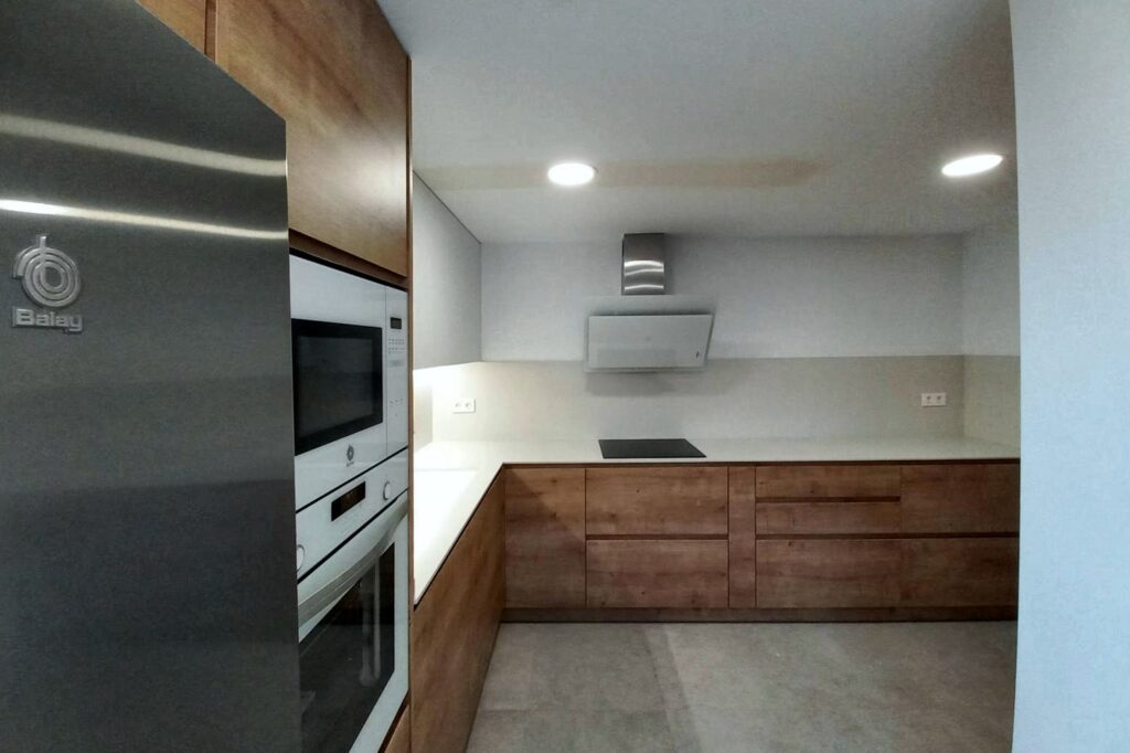 Cocina con frigorífico integrado en la columna de madera