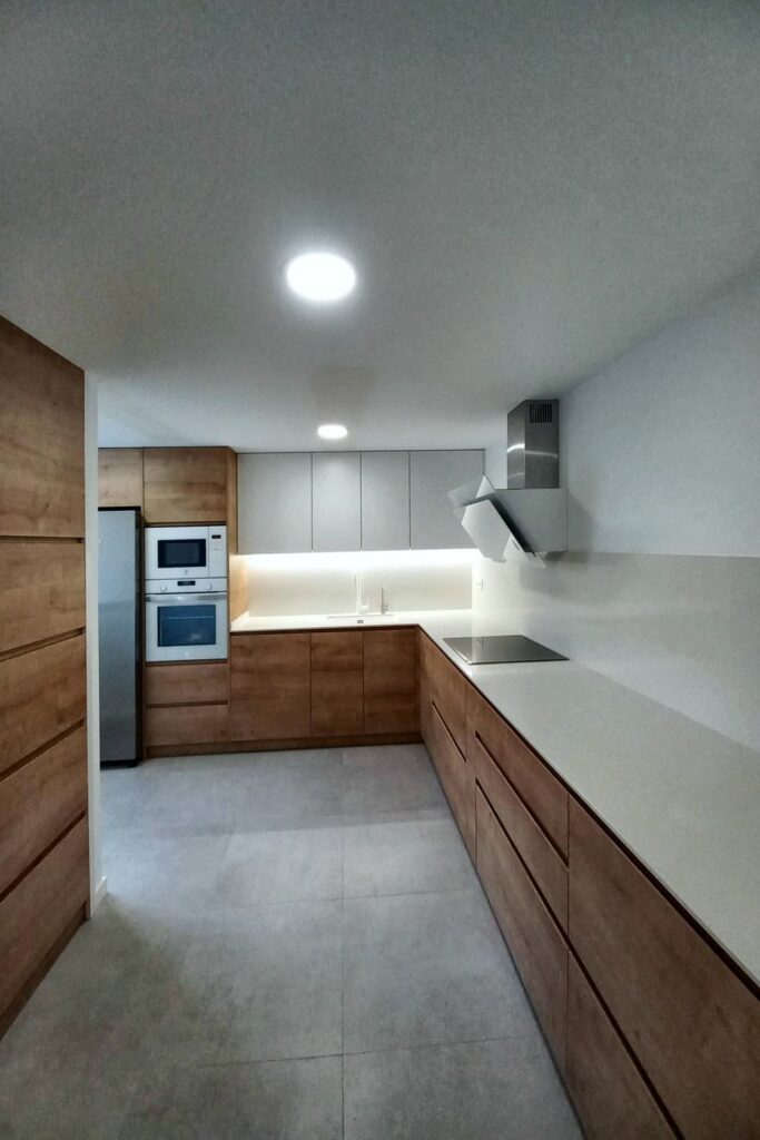 Cocina en L con revestimiento de madera en la pared