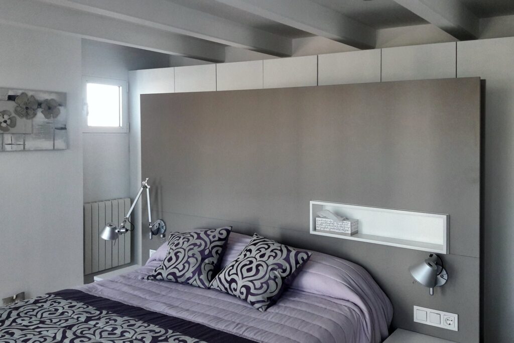 Dormitorio con techo de vigas y cabecero de madera