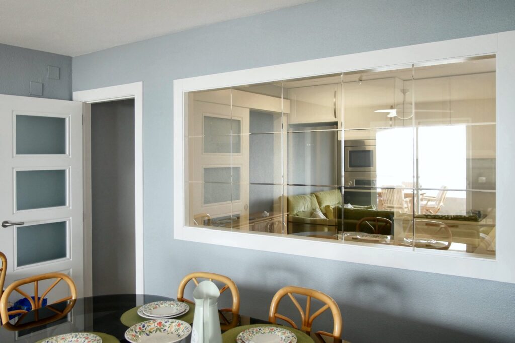 Comedor con ventana interior a la cocina y puertas lacadas