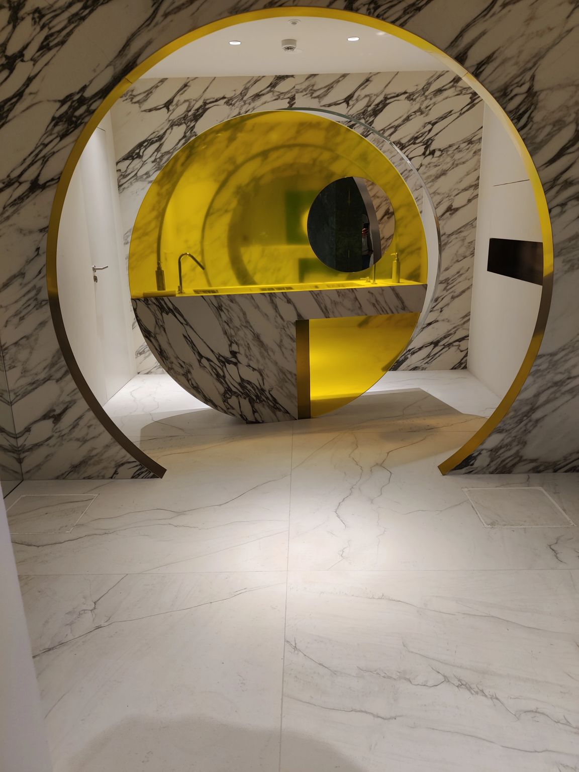 Ambiente circular con revestimiento de mármol y detalles en amarillo