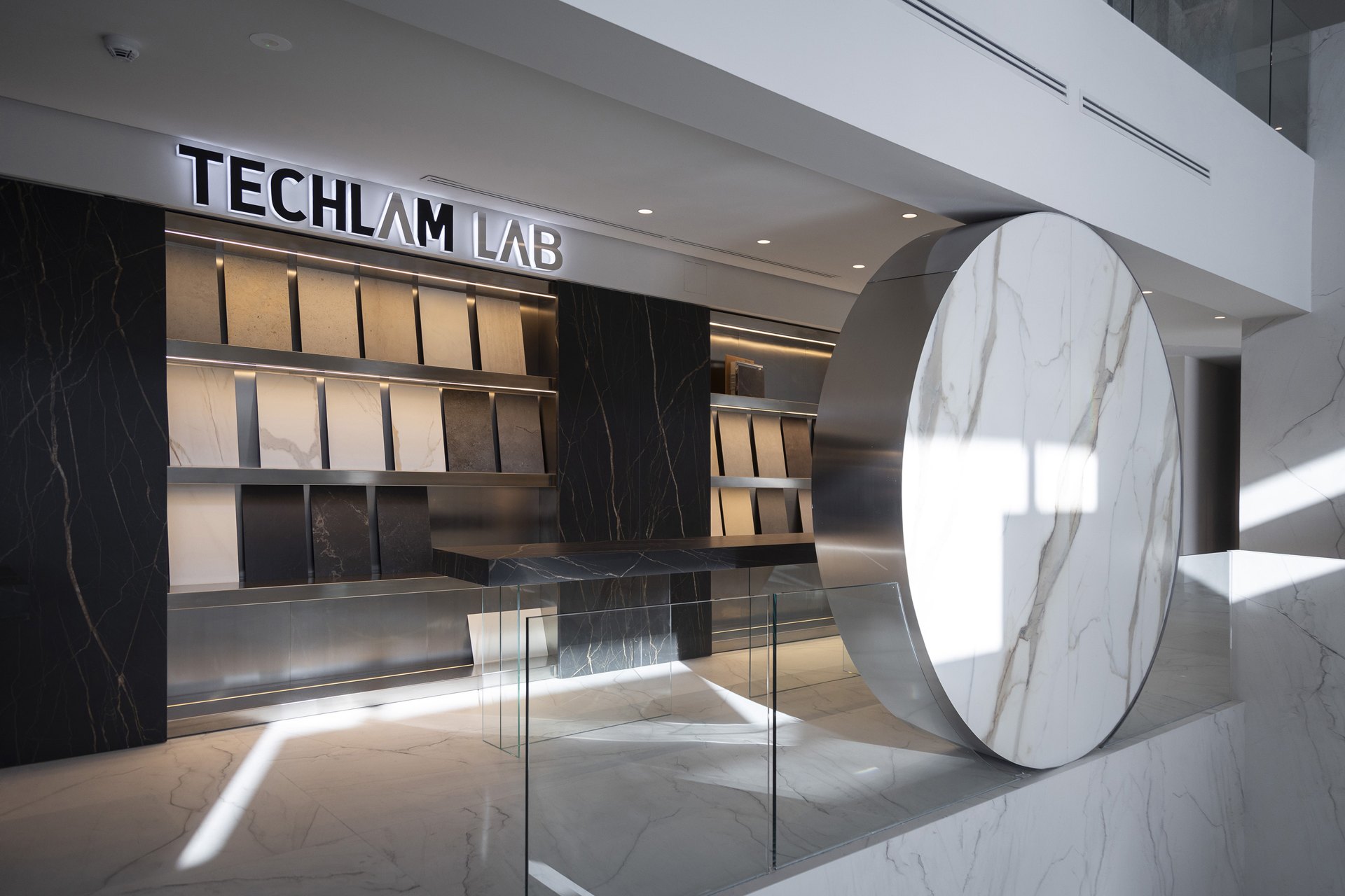 Zona técnica Techlam Lab con ceramoteca, mesa volada y círculo